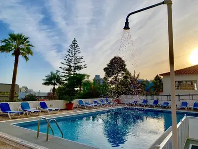 a swimming pool with blue chairs and a street light at Black & White by Homie in Funchal