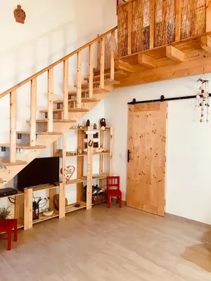 a loft with a wooden staircase and a sliding door at CASA BIKAS in Barão de São Miguel