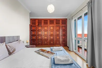 a bedroom with a white bed and a large window at Cumbres Villa in Funchal
