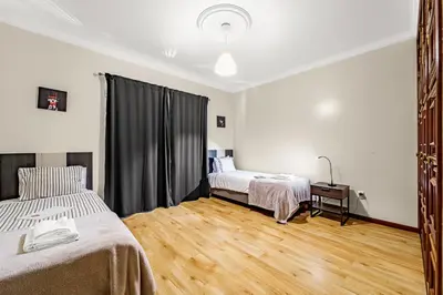 a bedroom with two beds and a wooden floor at Cumbres Villa in Funchal