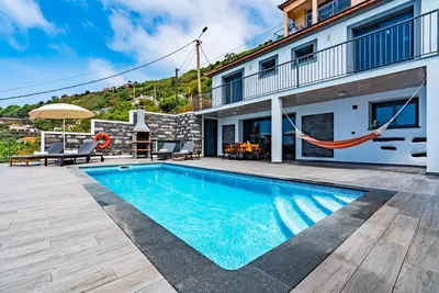 a villa with a swimming pool with a hammock at Villa da Bisa with heated swiming pool in Arco da Calheta