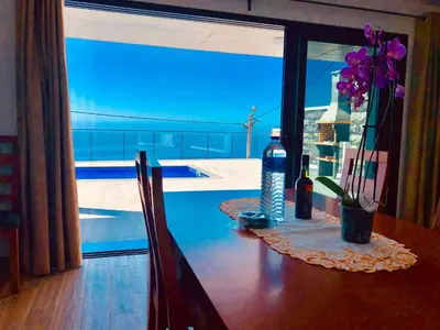 two wine glasses sitting on a table with a bottle of wine at Villa da Bisa with heated swiming pool in Arco da Calheta