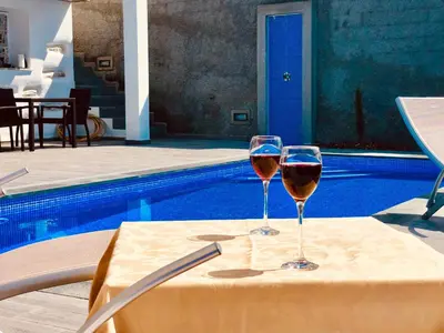 a patio with an umbrella and chairs and a pool at Villa da Bisa with heated swiming pool in Arco da Calheta