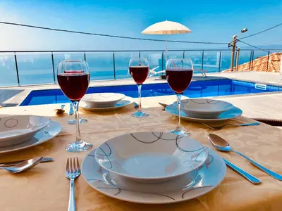 a table with glasses of wine on top of a building at Villa da Bisa with heated swiming pool in Arco da Calheta