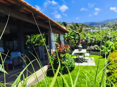 a house with a garden with flowers and plants at Les Terrasses Suites in Calheta