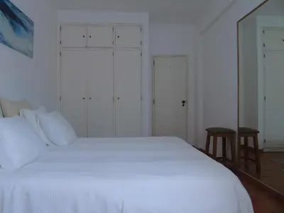 a white bed in a white bedroom with a stool at Cantinho Das Estrelas, Luz Lagos in Luz