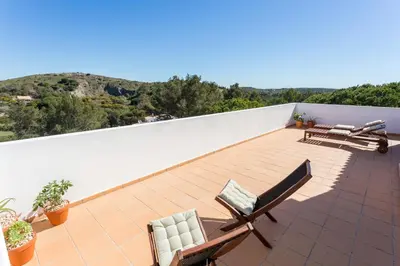 a patio with two chairs and a table on a roof at Salema Family Home in Salema