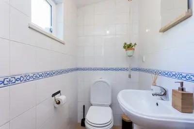 a white bathroom with a toilet and a sink at Salema Family Home in Salema