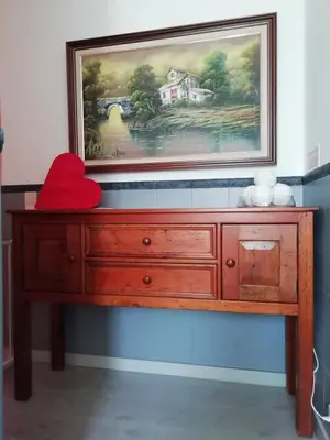 a painting above a wooden dresser with a red pillow at Burgau125 - villa near the beach in Vila do Bispo