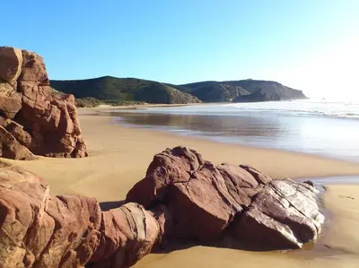 a sandy beach with large rocks in the sand at Villa Nooma in Carrapateira