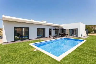 a villa with a swimming pool in front of a house at Villa Nooma in Carrapateira