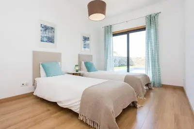 two beds in a room with a window at Villa Nooma in Carrapateira