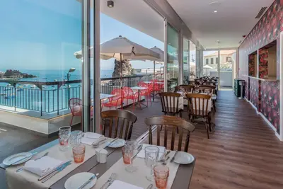 a restaurant with tables and chairs and a view of the ocean at Pestana Churchill Bay in Câmara de Lobos