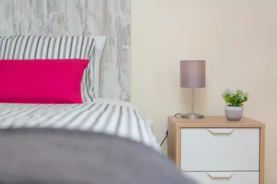 a bed with a pink pillow and a table with a lamp at Villa Vista Mar in Funchal