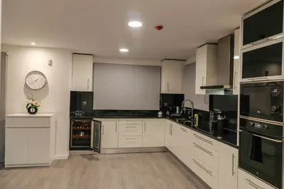 a kitchen with white cabinets and a clock on the wall at A&M House II Luxury Holidays Home in Arco da Calheta