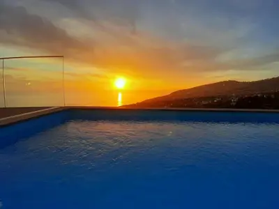a swimming pool with a sunset in the background at A&M House II Luxury Holidays Home in Arco da Calheta