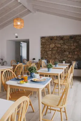 a dining room with tables and chairs and a stone wall at Pure Fonte Velha B&B in Vila do Bispo