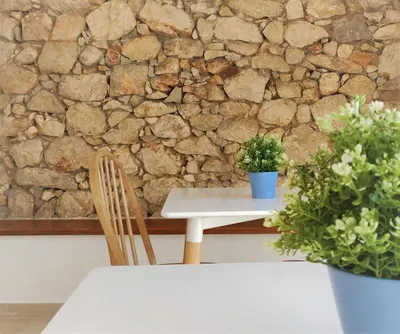 a table and a chair and a stone wall at Pure Fonte Velha B&B in Vila do Bispo