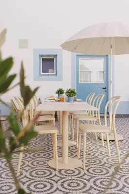 a dining room with a table and chairs with an umbrella at Pure Fonte Velha B&B in Vila do Bispo