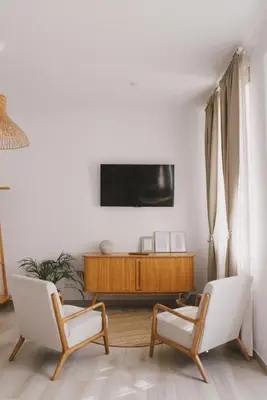 a living room with two chairs and a tv on a wall at Pure Fonte Velha B&B in Vila do Bispo