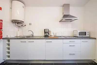 a kitchen with white cabinets and a microwave at Cayres Suites Carmo in Funchal