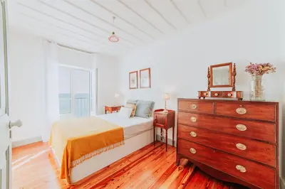 a bedroom with a bed and a dresser and a window at Casa da Praia in Câmara de Lobos