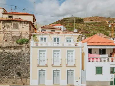 a white building in front of a mountain at Casa da Praia in Câmara de Lobos