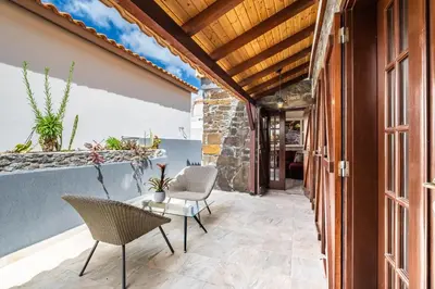 an outdoor patio with chairs and a table and a building at Recanto Jardim Do Mar in Jardim do Mar