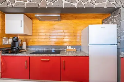 a kitchen with red cabinets and a white refrigerator at Recanto Jardim Do Mar in Jardim do Mar