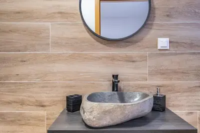 a bathroom with a stone sink and a mirror at Recanto Jardim Do Mar in Jardim do Mar