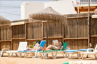 two people laying in lawn chairs on a beach at Sagres Sun Stay - Surf Camp & Hostel in Sagres