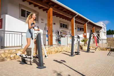 a woman standing on a treadmill in front of a building at Sagres Sun Stay - Surf Camp & Hostel in Sagres