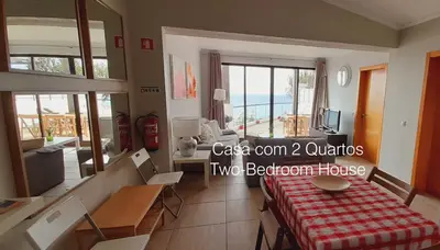a room with a bed and a table with a view of the ocean at First Balcony - Porto Santo in Porto Santo