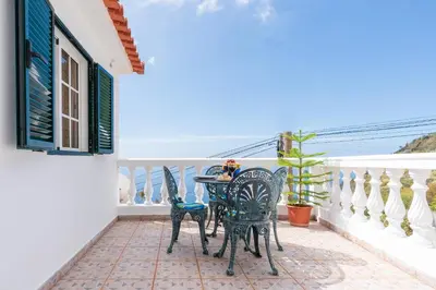 a table and chairs on a balcony with the view of the ocean at Apartamento Isabel in Achada de Cima