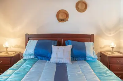 a bed with blue and white pillows and two night stands at Apartamento Isabel in Achada de Cima