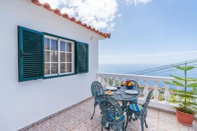 a table and chairs on a balcony with a view of the ocean at Apartamento Isabel in Achada de Cima