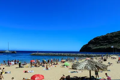 a group of people on a beach with the ocean at Machim House by AnaLodges in Machico