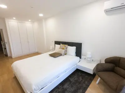 a white bedroom with a bed and a chair at Superior Rentals - Downtown Villa in Funchal