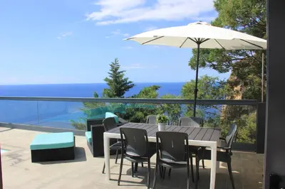 a table and chairs and an umbrella on a balcony at Sea House Madeira in Garajau