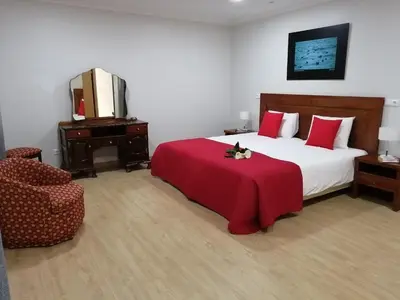 a bedroom with a bed with a red blanket and a chair at Lucilia's House in Calheta