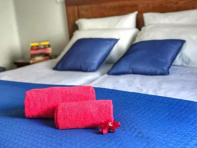 two beds with blue pillows and red towels on them at Lucilia's House in Calheta