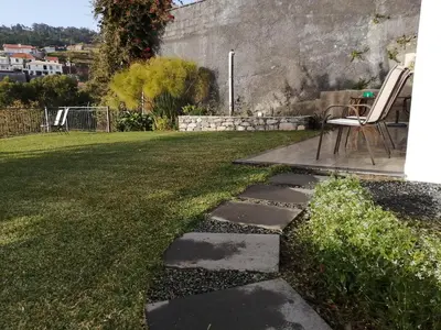 a garden with a table and a chair in a yard at Lucilia's House in Calheta