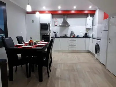a kitchen with a dining table and a kitchen with white cabinets at Lucilia's House in Calheta