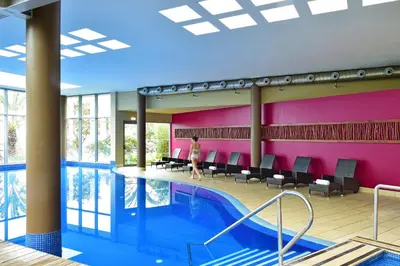 a person walking by a swimming pool in a building at Pestana Promenade Ocean Resort Hotel in Funchal