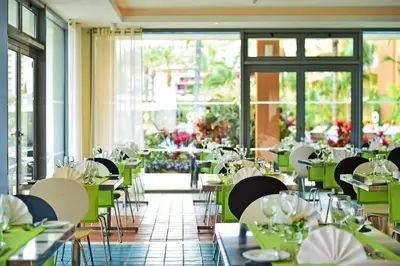 a dining room with tables and chairs and windows at Pestana Promenade Ocean Resort Hotel in Funchal