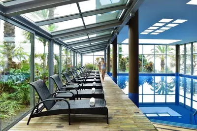 a row of chairs on a deck with a pool at Pestana Promenade Ocean Resort Hotel in Funchal