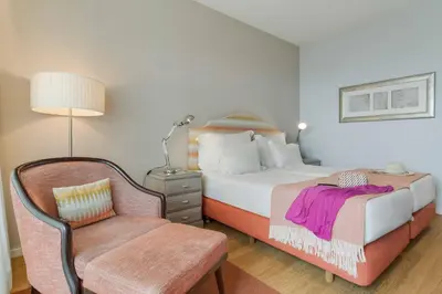 a hotel room with a bed and a chair at Pestana Promenade Ocean Resort Hotel in Funchal
