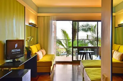 a living room with a couch and a television and a balcony at Pestana Promenade Ocean Resort Hotel in Funchal