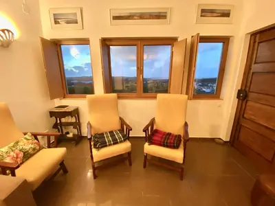 a room with two chairs and a table and windows at Casa do Miradouro in Carrapateira