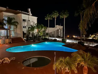 a swimming pool at night with palm trees and a building at Lagos Vila Mós 59 in Lagos